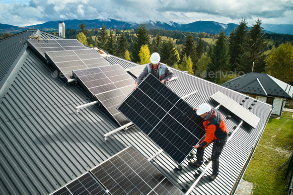 Workers installing solar panels on a roof of house Workers installing solar panels on a roof of house. Solar battery installation in mountains. Concept of alternative energy.